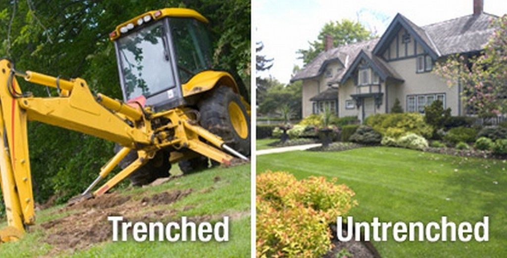 Image of a Trenched yard. Backhoe digging trench in a front lawn. To the left is a home with a non tenched yard.